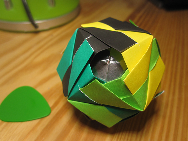 The Etna Kusudama model. The shape symmetry group is that of a cube, and a single face of the cube is facing the camera. The four edges around that face are colored black, yellow, light green, dark green.