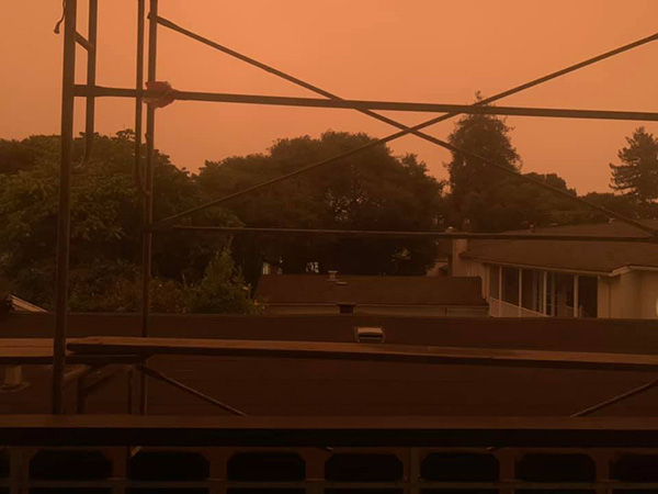 photo of orange sky, as seen from a balcony, with some scaffolding in the way