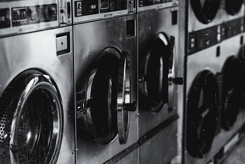 A grayscale photo of washing machines in a row