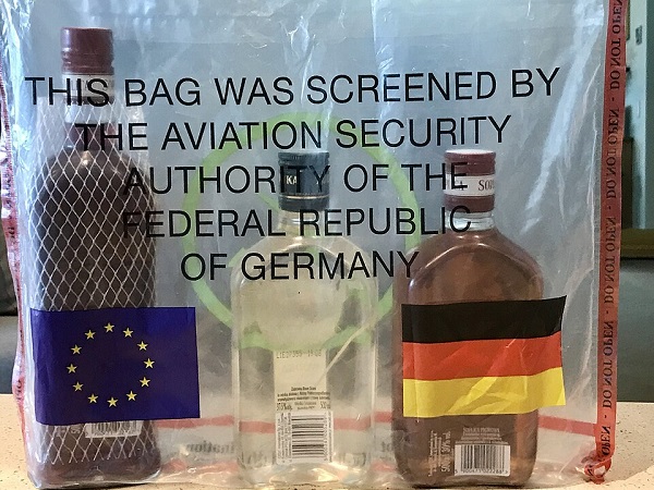 A clear plastic bag with bottles inside, reading "This bag was screened by the aviation security authority of the Federal Republic of Germany"