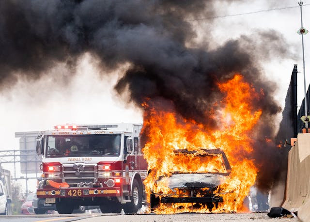 A wrecked car engulfed in flames