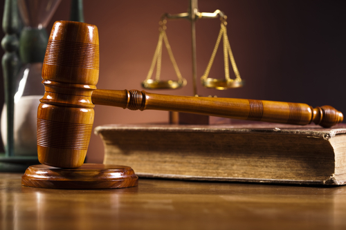 A gavel resting in front of a set of scales