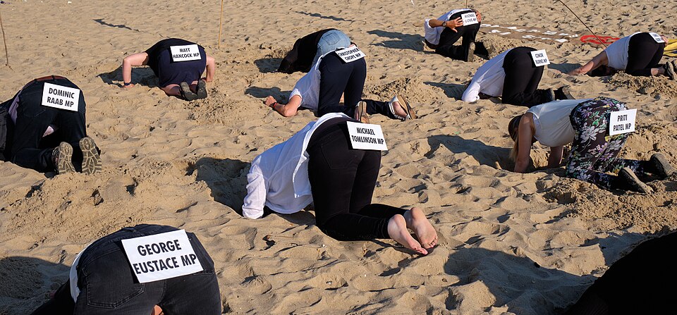 A group of protesters symbolically sticking their heads in the sand