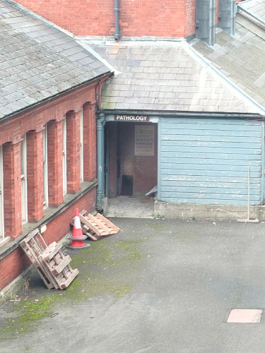 A zoomed-in photo of the previous driveway are, however the doorway in the back is visible and labled 'Pathology.'